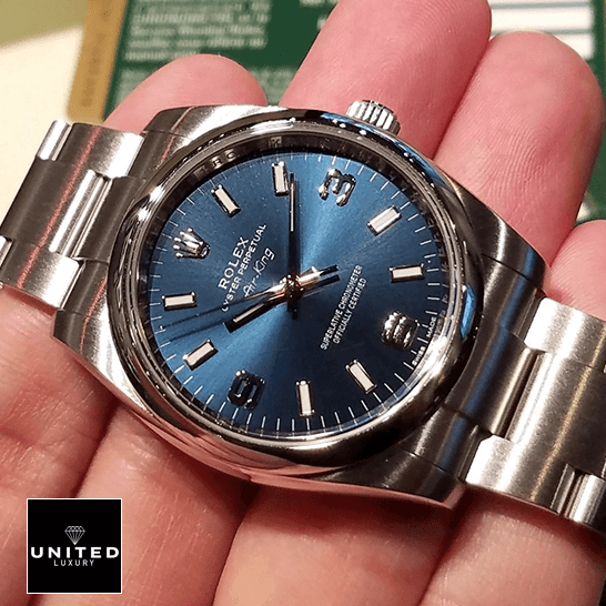 Rolex Air King 114200 Blue Dial  on the hand and next to warranty card