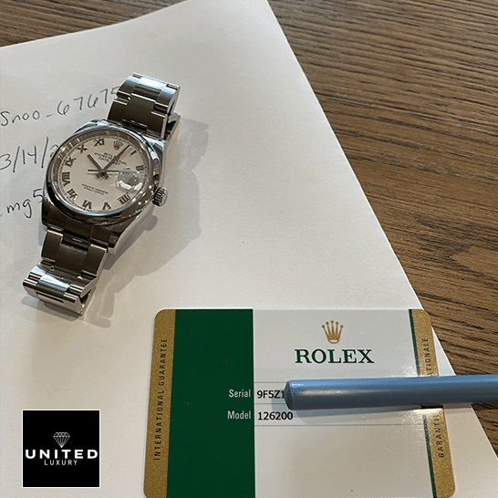 Rolex datejust  watch and warranty card on the table